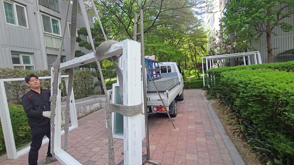 구미동 무지개마을대림 45평 샷시 교체 — 단지 밖 도로에서 새 샷시 틀에 줄을 거는 시공팀